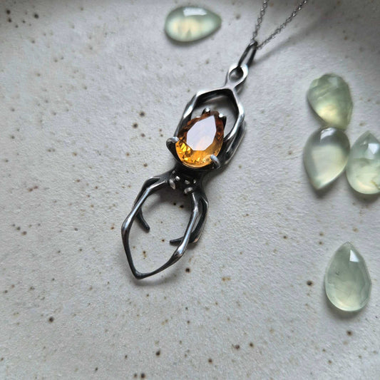 Handmade silver Spider necklace featuring a golden citrine gemstone, arranged in a flat lay