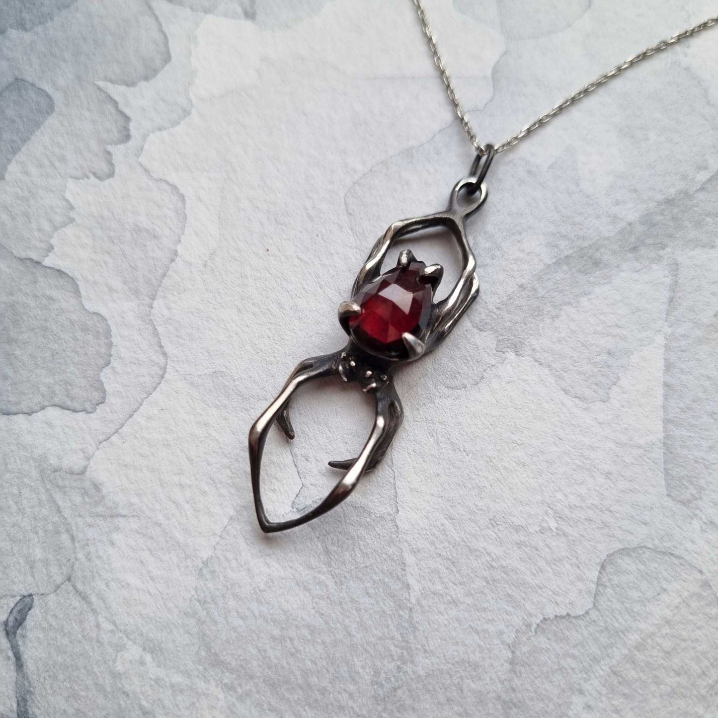 Silver spider necklace resting on textured background – bold oxidized silver jewelry