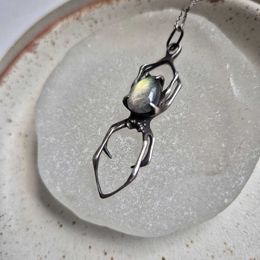 Sterling silver Spider pendant with glowing labradorite, flat lay