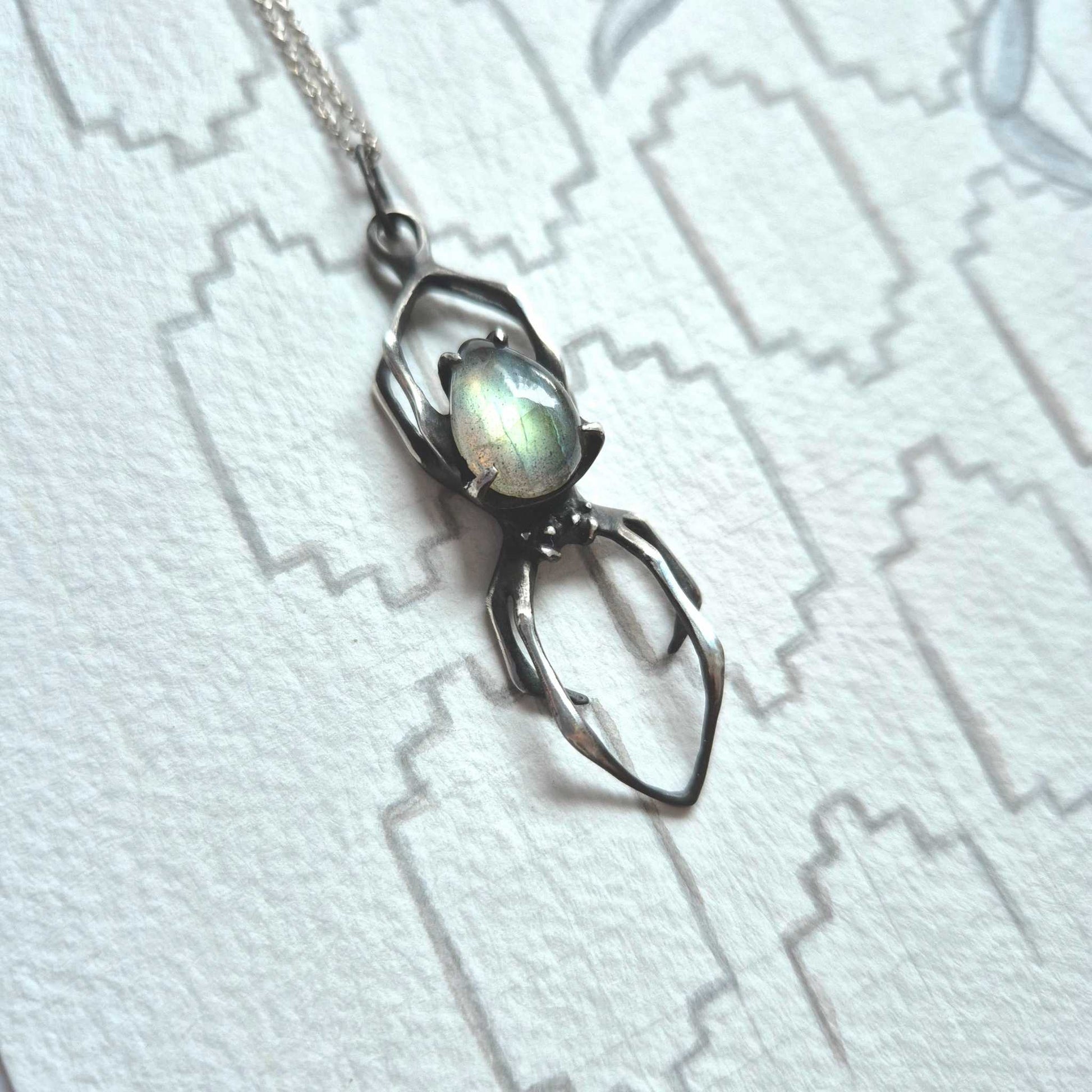 Textured Spider pendant with labradorite, laying flat on patterned background