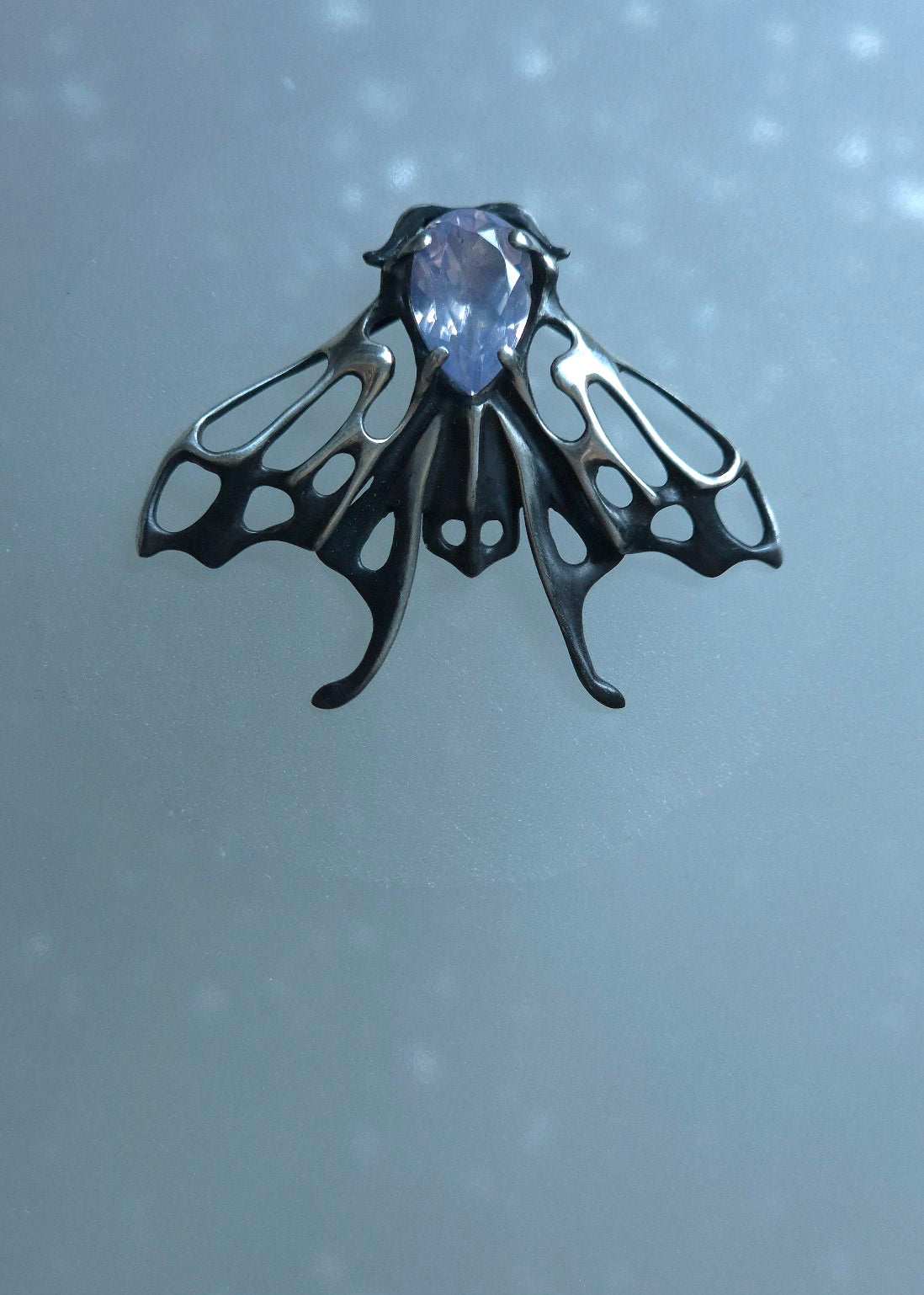 Mystical silver Moth necklace with pale quartz cabochon reflecting soft ambient light
