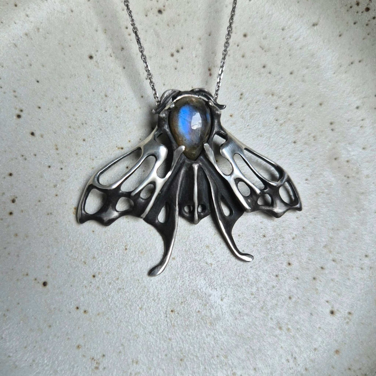 Handcrafted silver Moth necklace featuring a glowing blue labradorite