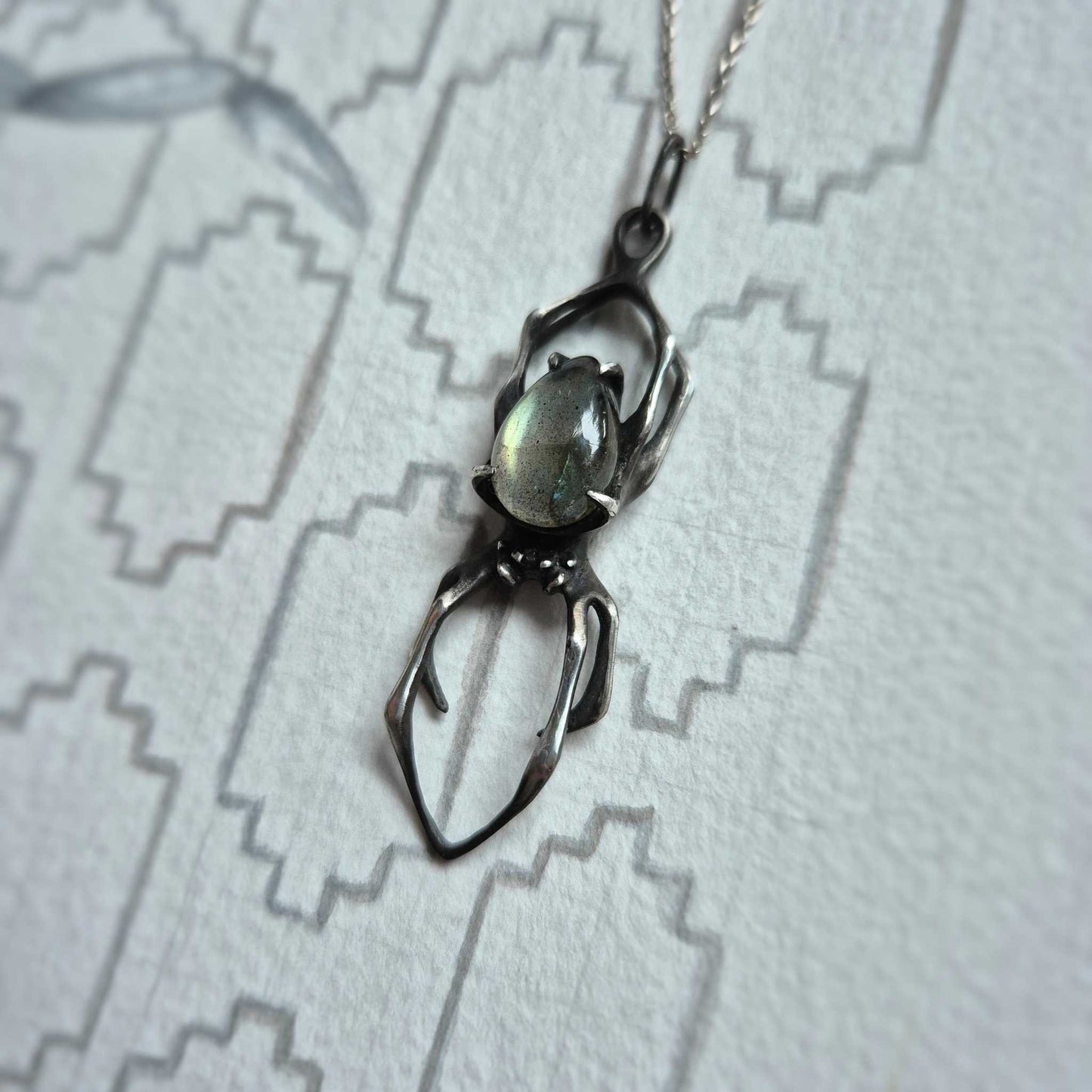 Sculptural silver Spider necklace with labradorite on abstract linear backdrop