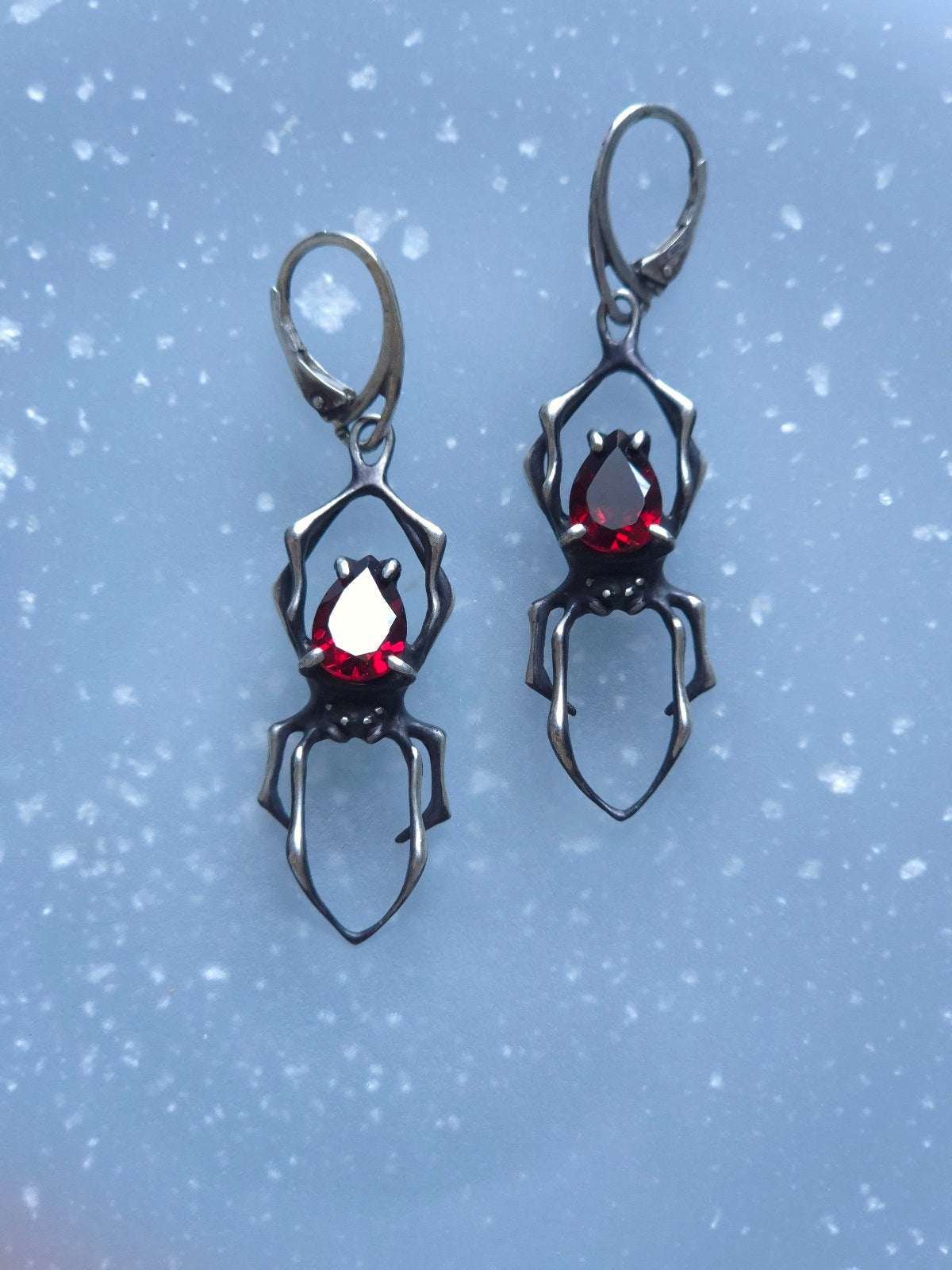 Artisanal silver spider earrings made from oxidized silver, featuring natural garnet gemstones