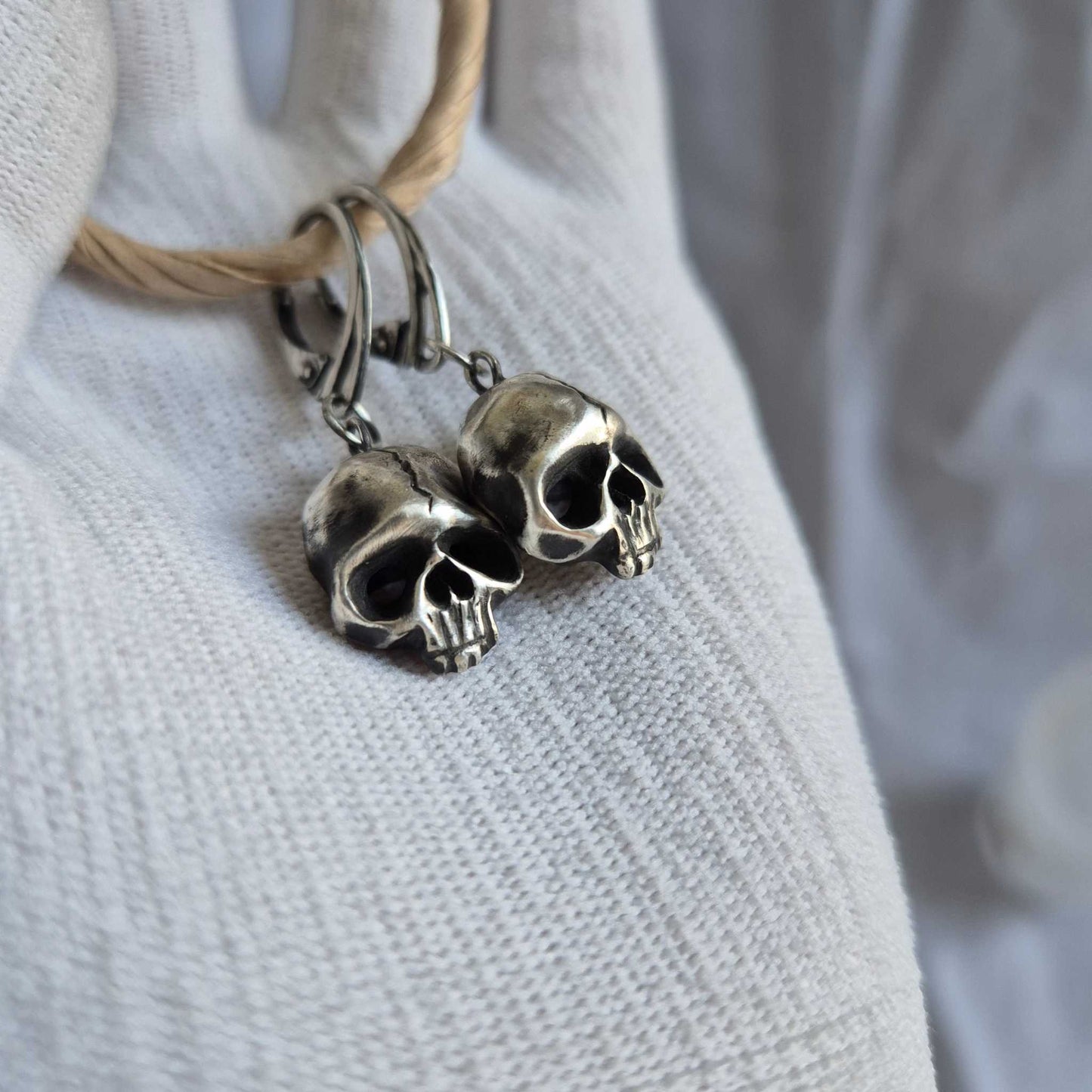 Silver Skull earrings captured from the side, emphasizing their three-dimensional form and eerie elegance.