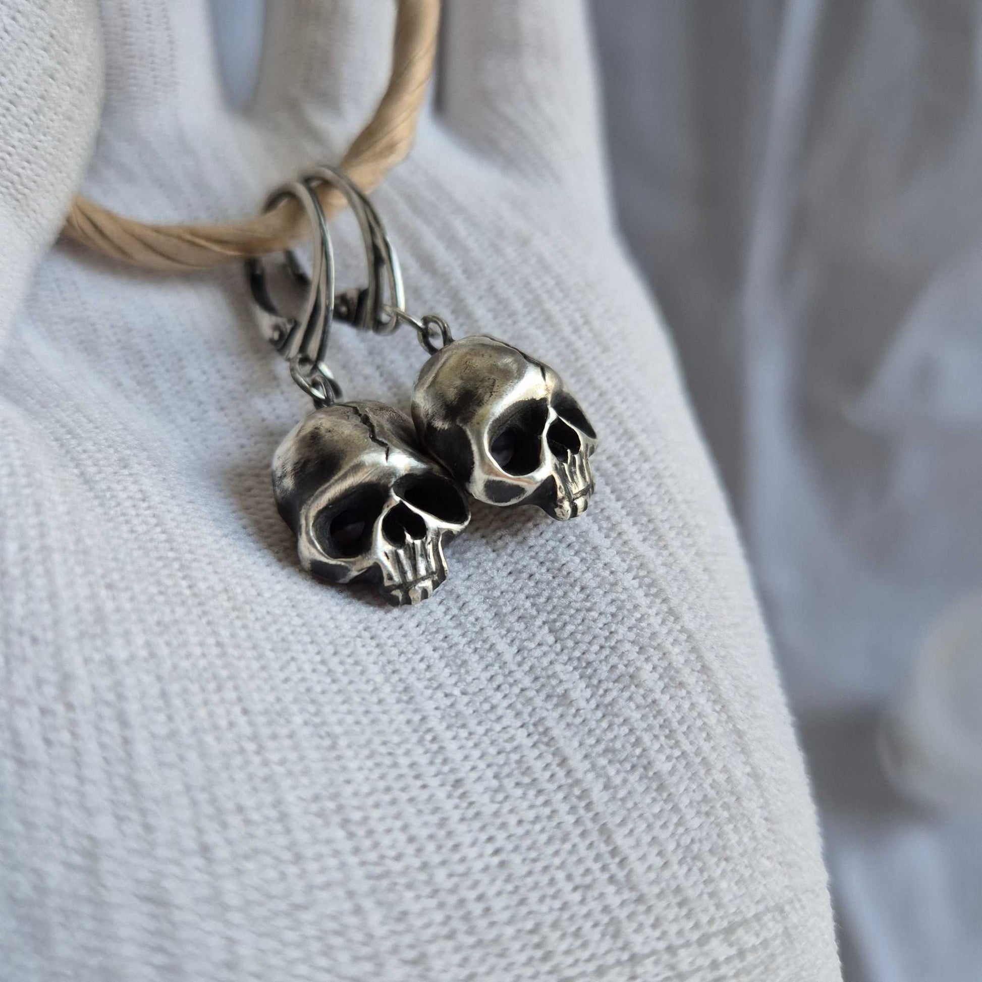 Silver Skull earrings captured from the side, emphasizing their three-dimensional form and eerie elegance.