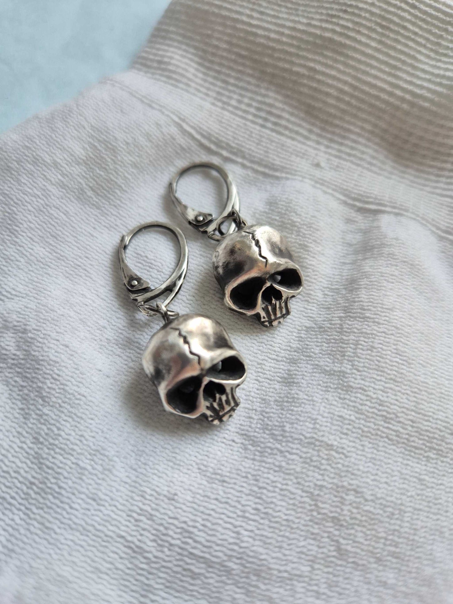 Top view of silver skull earrings highlighting details