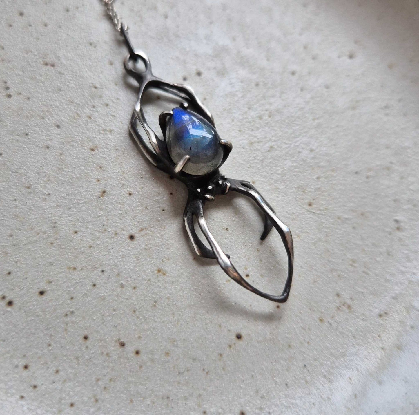 Blue labradorite silver Spider necklace shot from the side to show gemstone flash and sculptural silver legs.