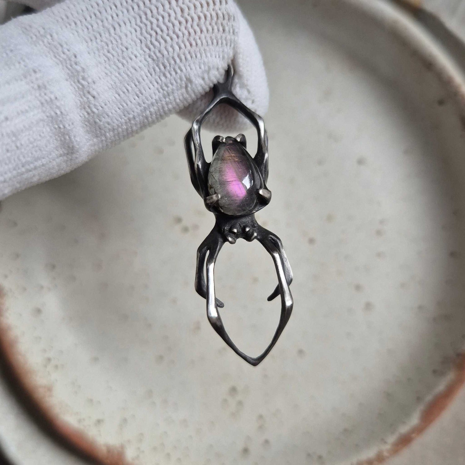 Silver Spider necklace with purple labradorite — close-up of textured silver and pear-shaped gemstone on ceramic plate