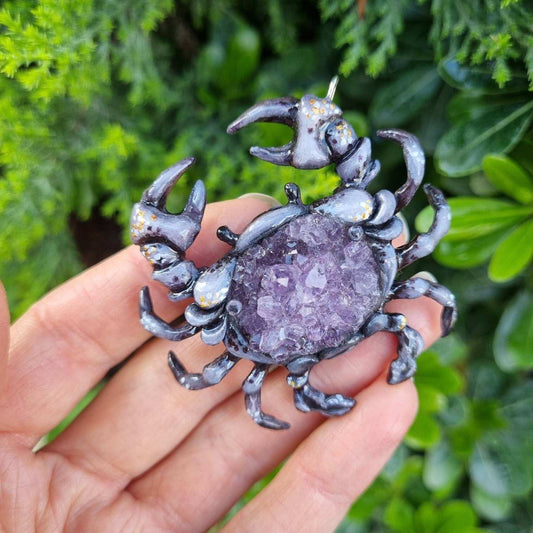 Sculpted Crab necklace featuring natural amethyst crystal, shown outdoors in bright light.