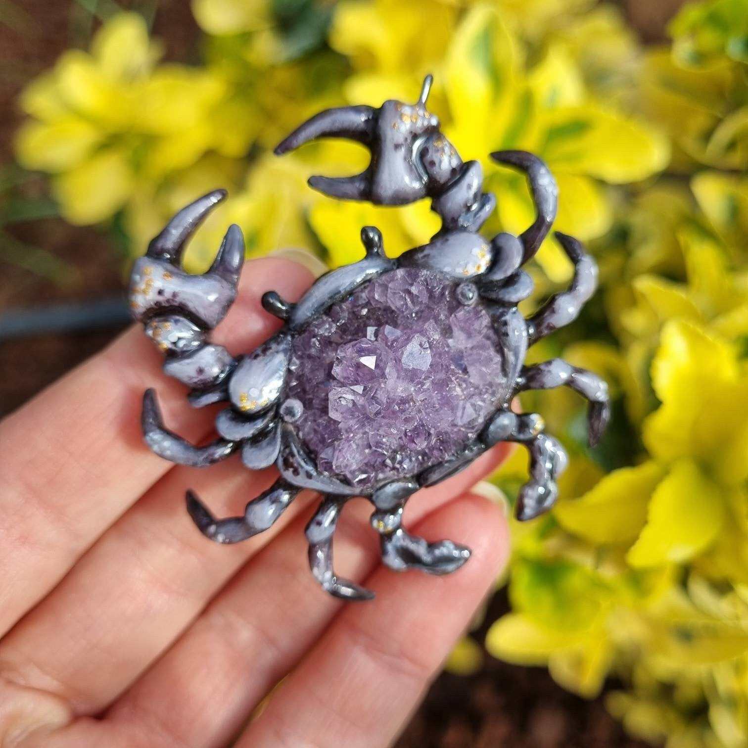 Amethyst crab talisman photographed in hand with vivid yellow leaves in background.
