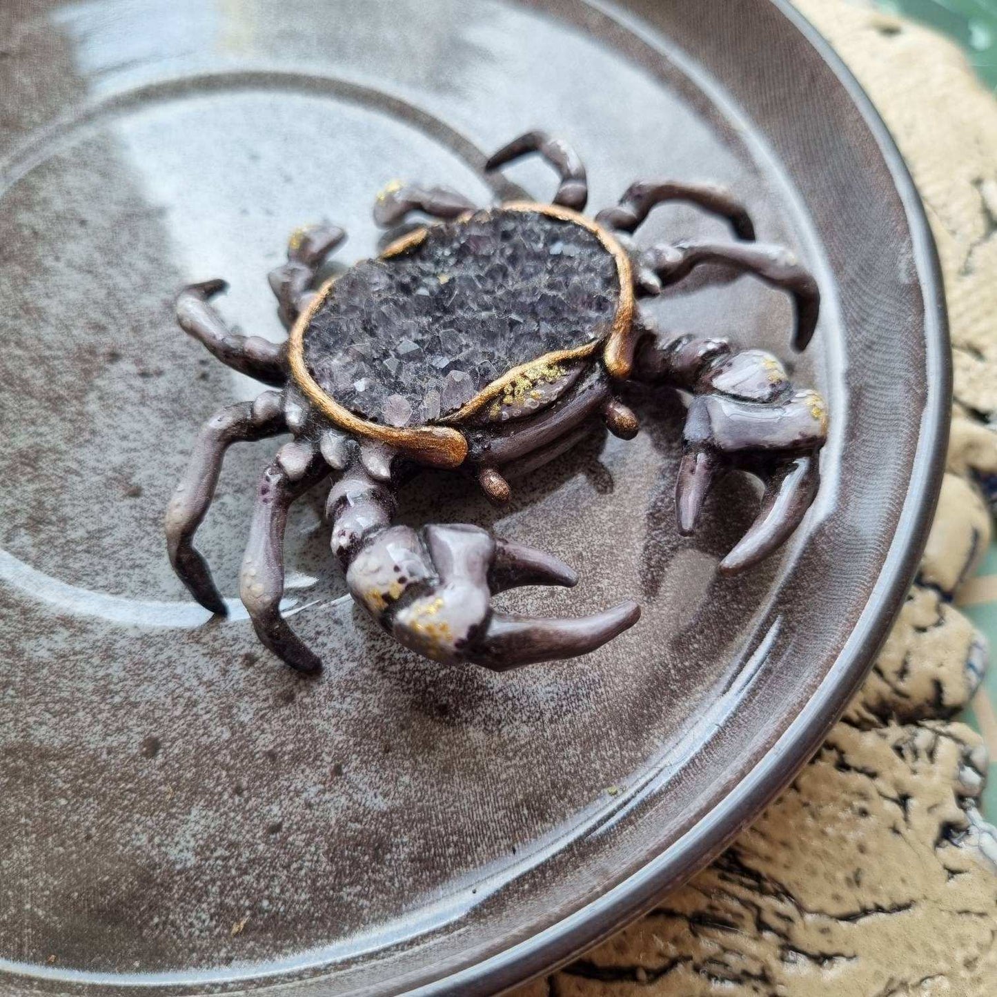 Resin crab sculpture with natural smoky quartz, displayed on a plate.