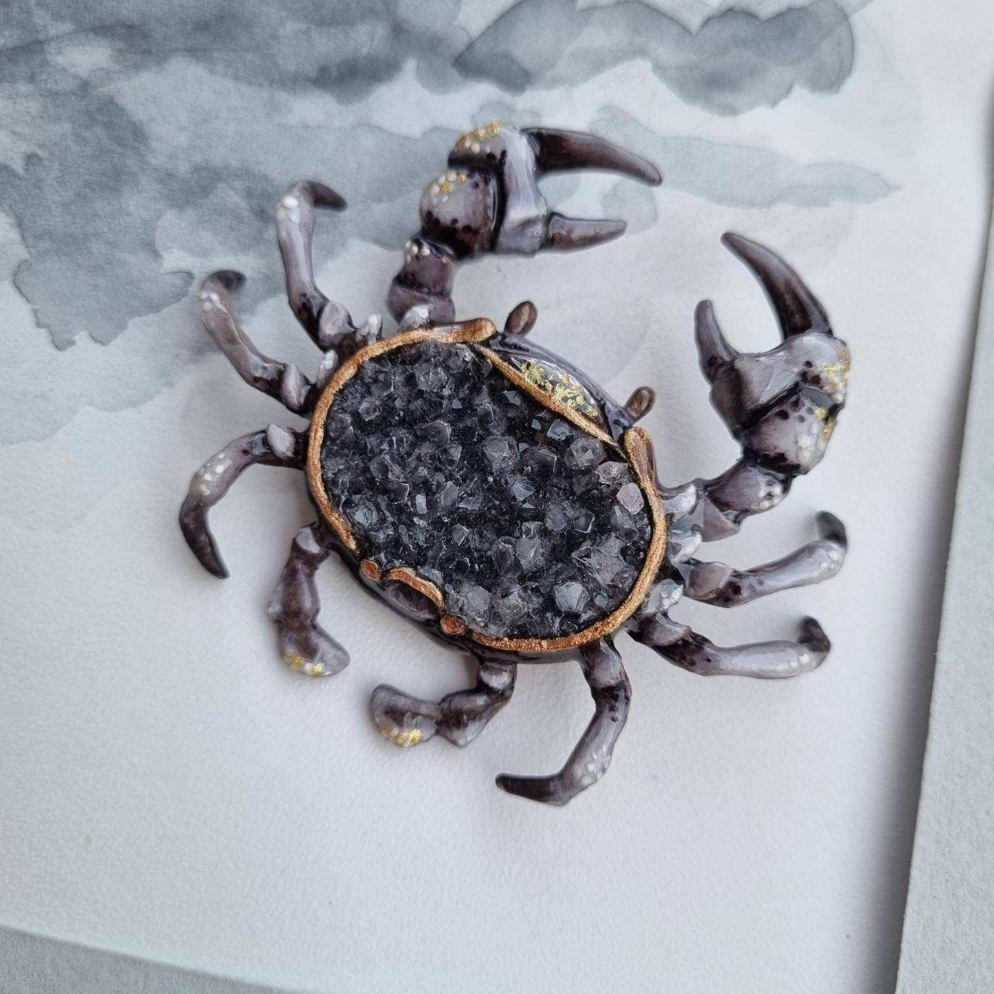Crab figurine with natural crystal back, on textured paper.