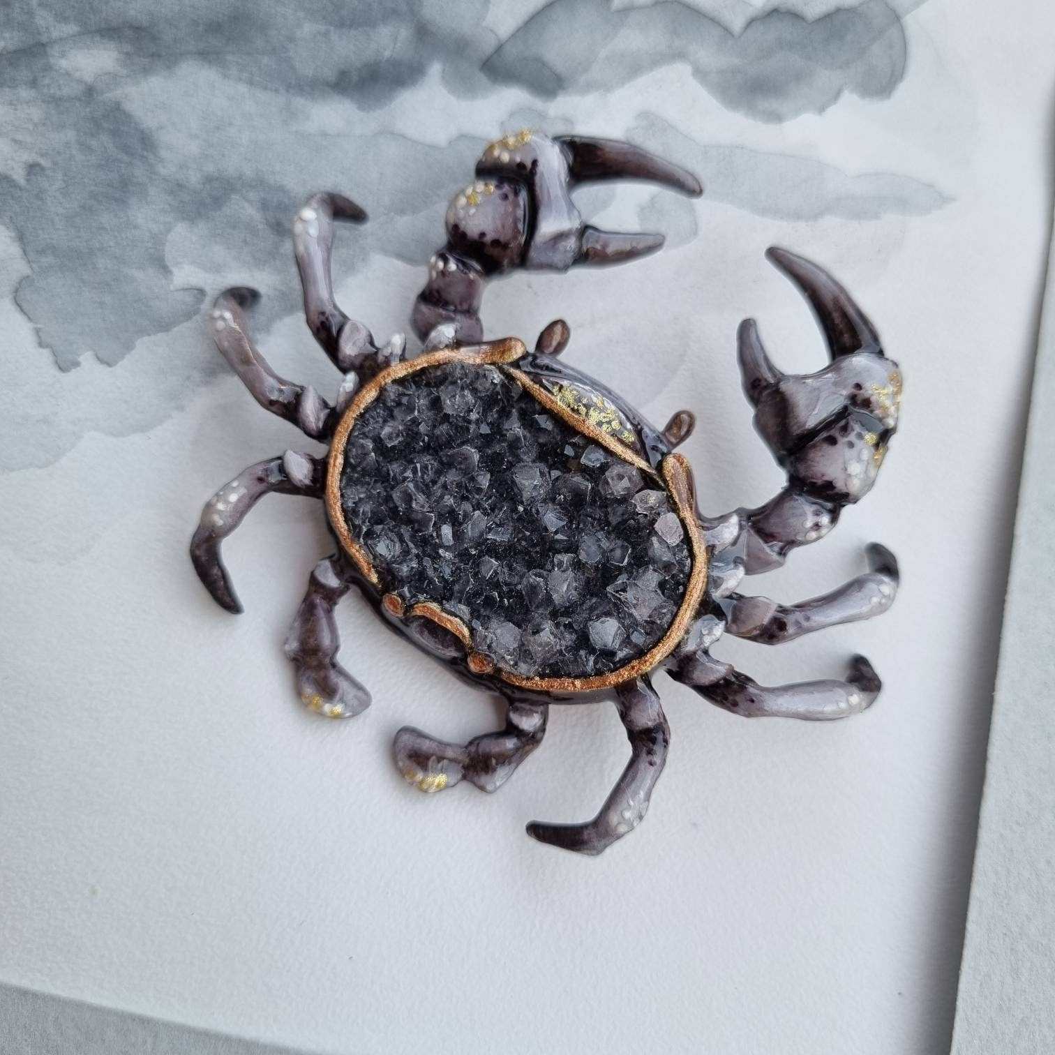 Crab figurine with natural crystal back, on textured paper.