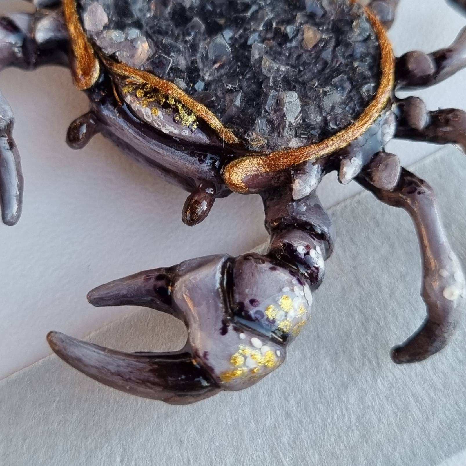 Side angle of crab figurine with dark quartz crystals, claws in focus.