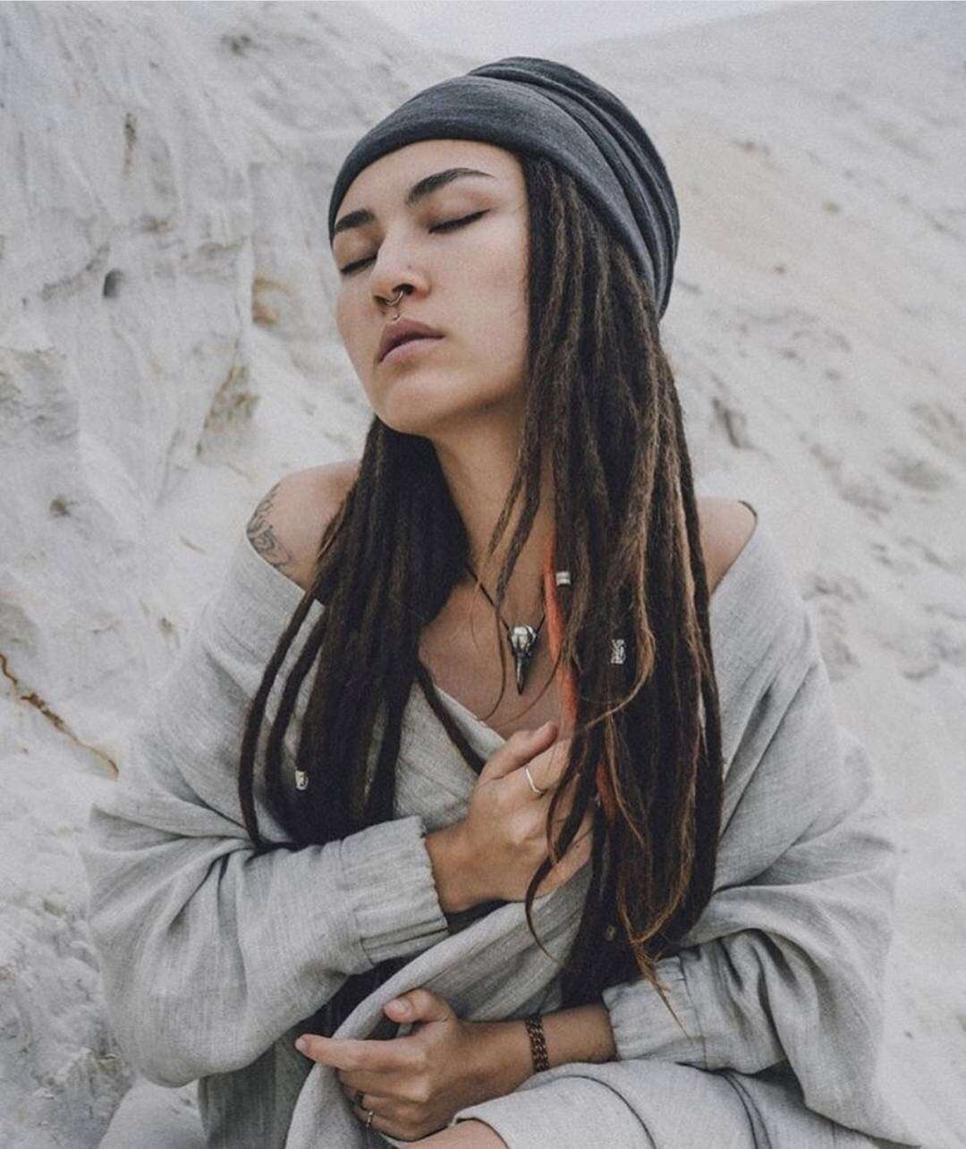 Model with serene expression wearing skull pendant over layered clothing.