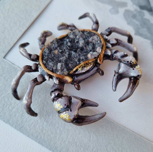 Handcrafted crab figurine with smoky quartz druzy, placed on a light surface.