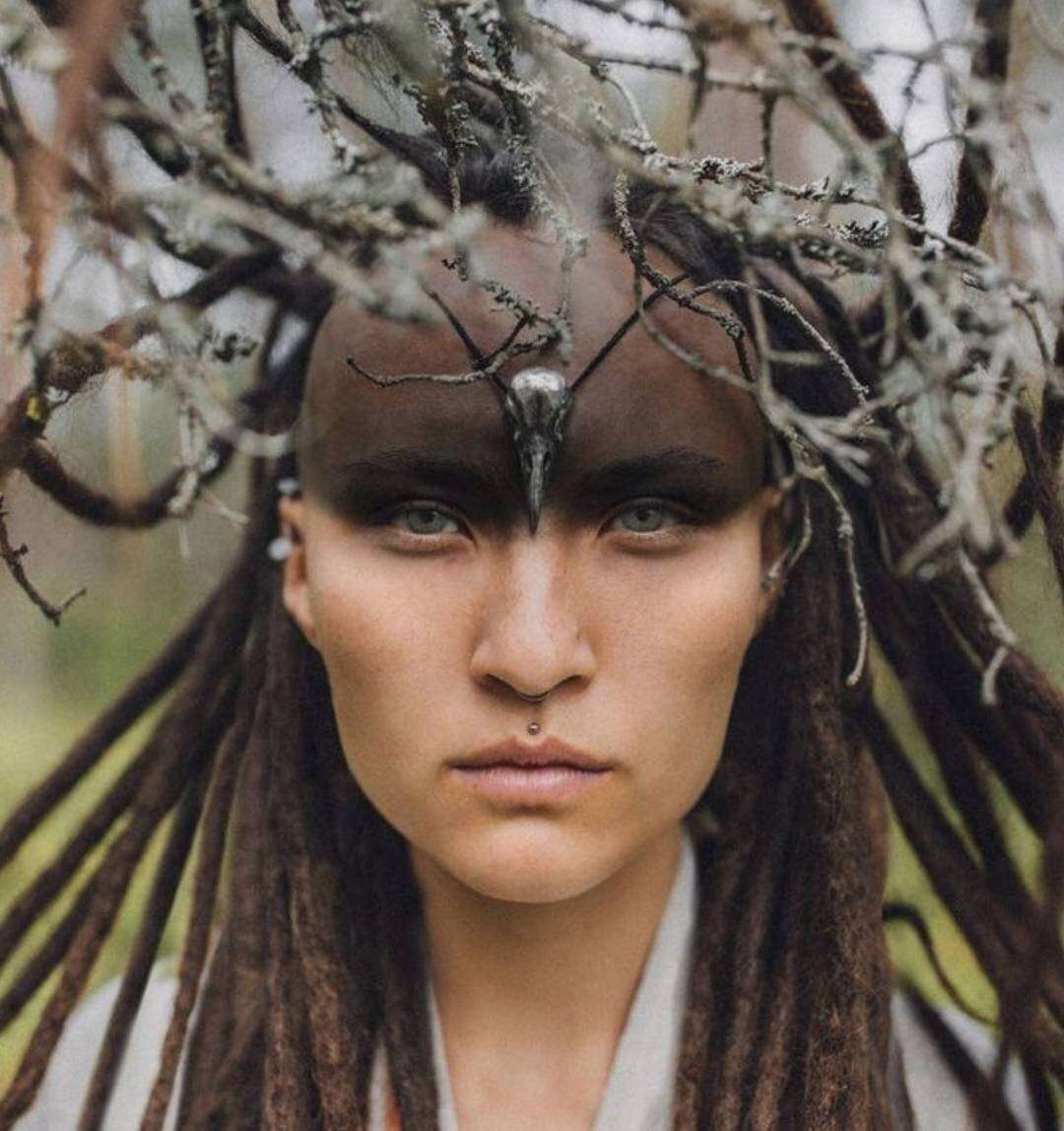 Model in forest crown wearing silver skull necklace as talismanic adornment.