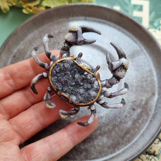 Smoky quartz crab figurine resting in hand, showing scale and crystal texture.