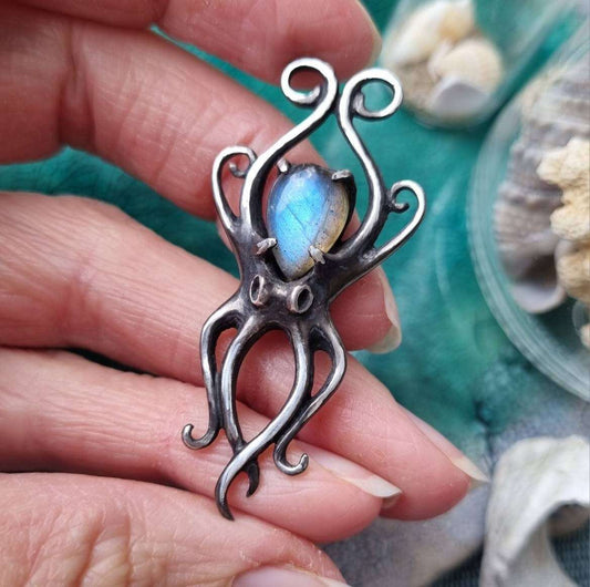 Handmade silver Octopus pendant featuring blue labradorite, shown held in hand.