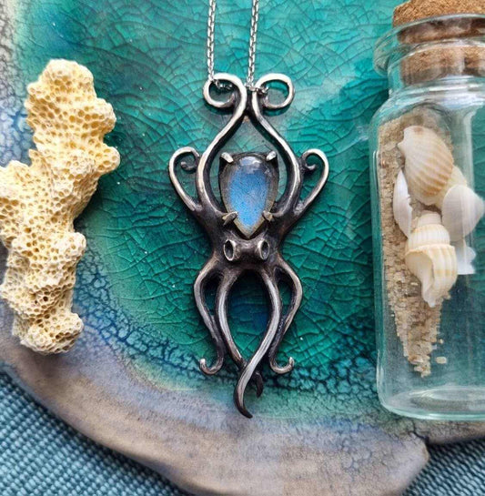 Silver Octopus necklace with blue labradorite, displayed on teal background with seashells.