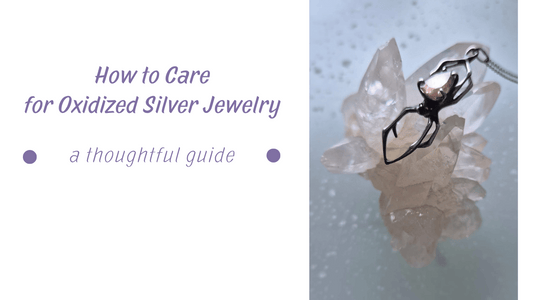 Jewelry care - Close-up of oxidized silver spider pendant with a soft pinkish golden gemstone, resting on a clear crystal cluster