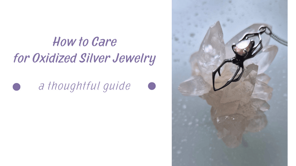 Jewelry care - Close-up of oxidized silver spider pendant with a soft pinkish golden gemstone, resting on a clear crystal cluster