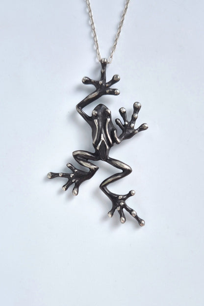 Front view of a leaping sterling silver frog necklace with chain on a white background
