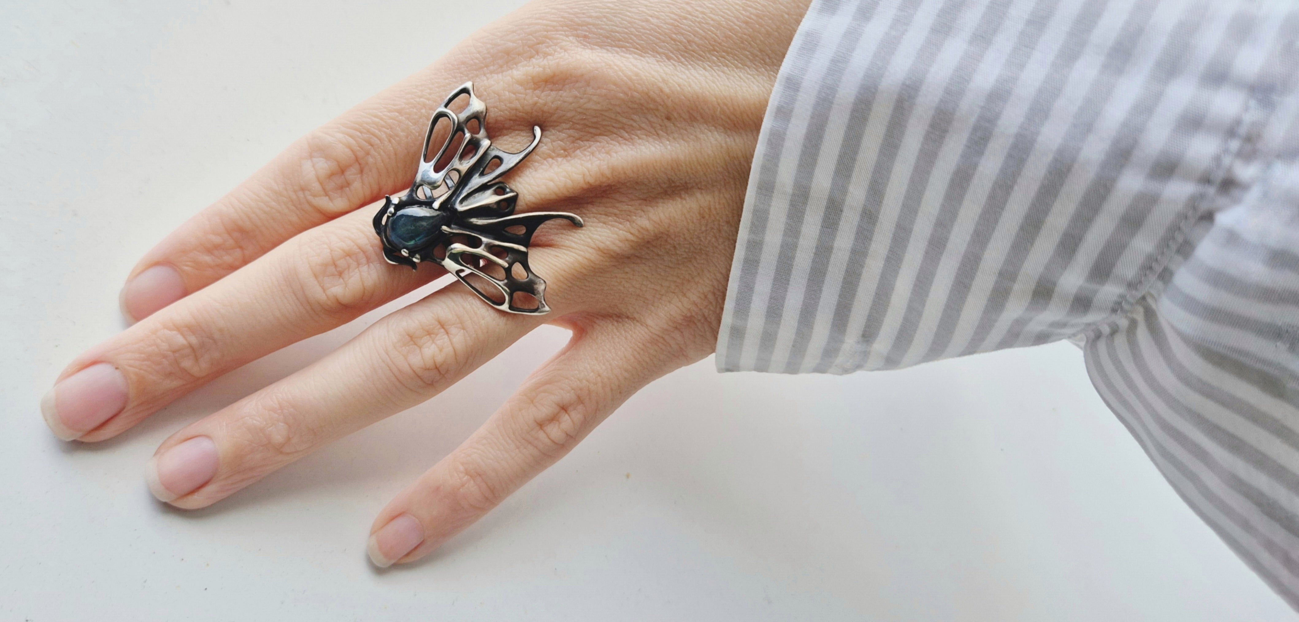 Woman wearing a sculptural moth ring in sterling silver
