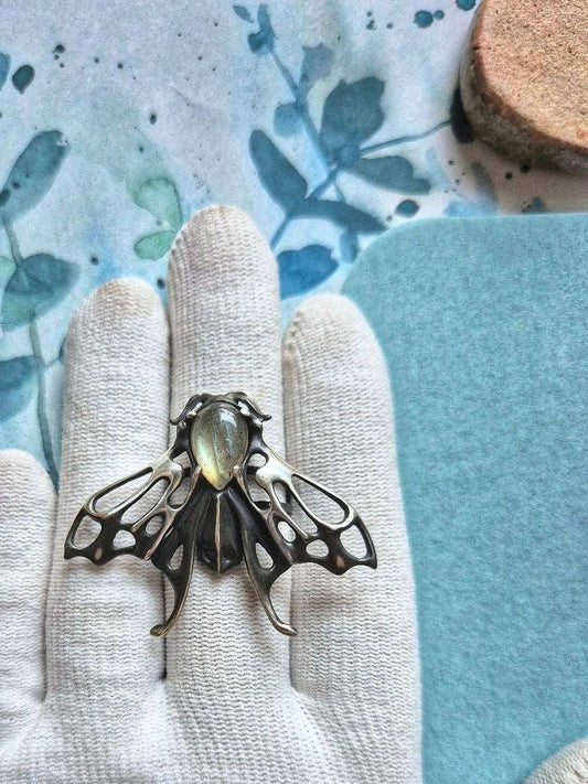 Detailed silver Moth ring with silvery labradorite shown on white glove, handcrafted fantasy jewelry