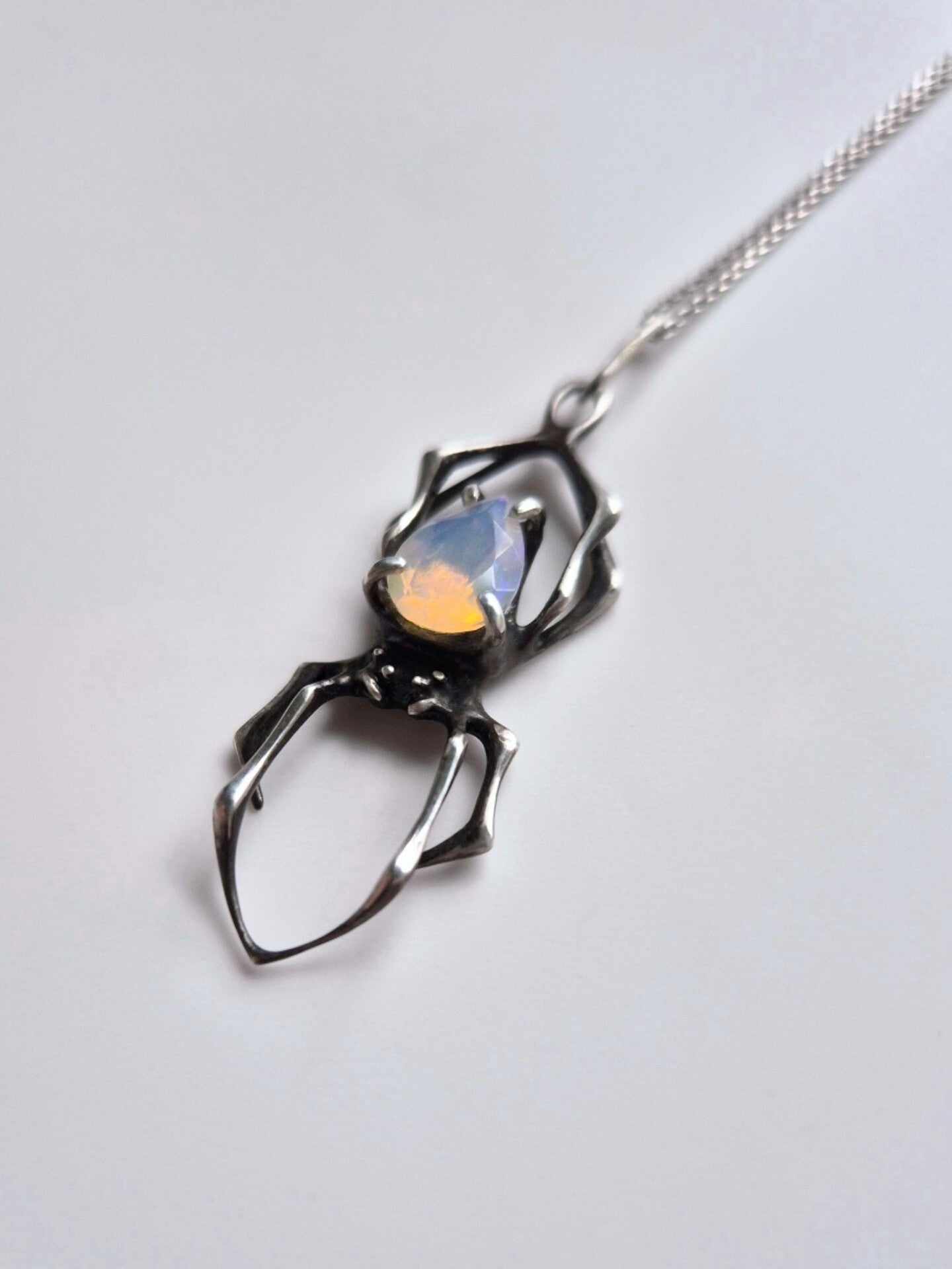 Spider pendant in silver with natural Opal gem on white background