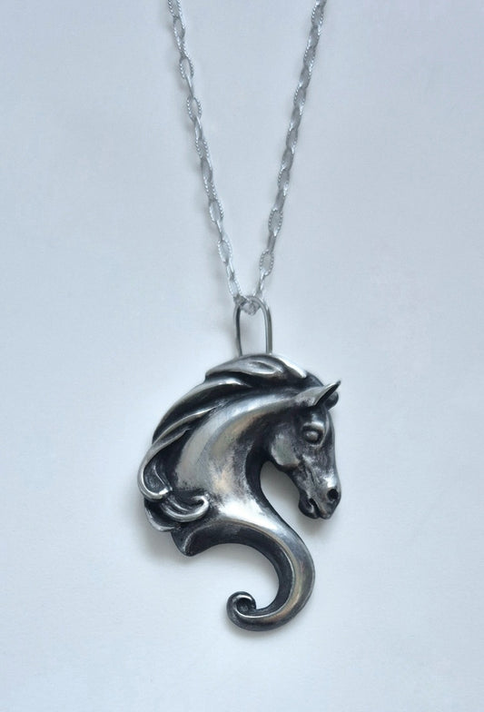 Full view of the sculptural sterling silver horse pendant on a silver chain