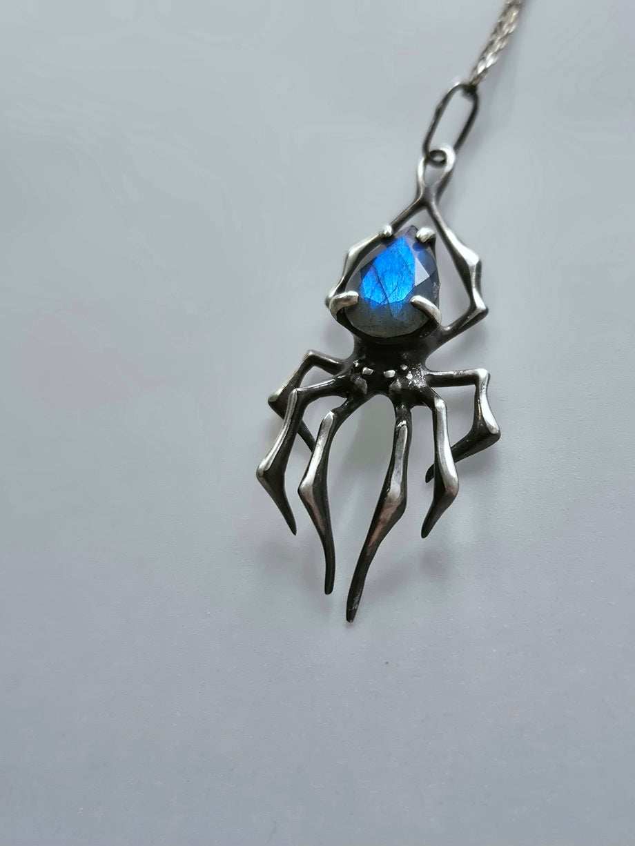 Close-up of handcrafted spider necklace featuring shimmering blue labradorite stone
