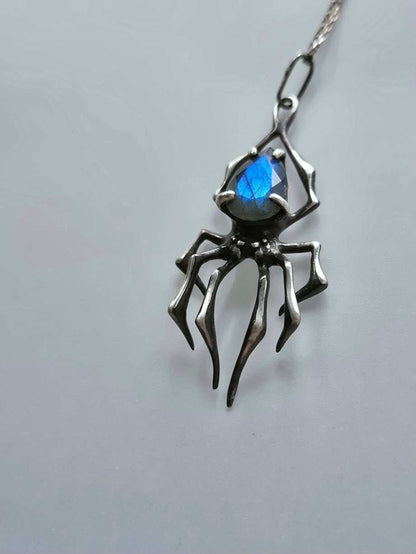 Close-up of handcrafted spider necklace featuring shimmering blue labradorite stone