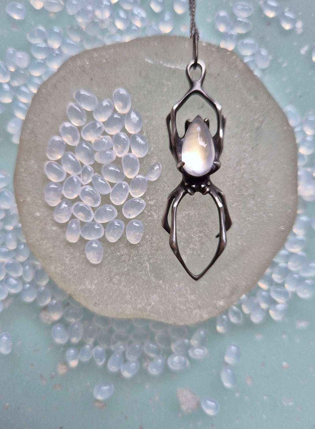 Moonstone spider pendant displayed on round glass dish