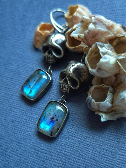 handmade oxidized silver Skull earrings with labradorites, on a blue background, with barnacles and seashells