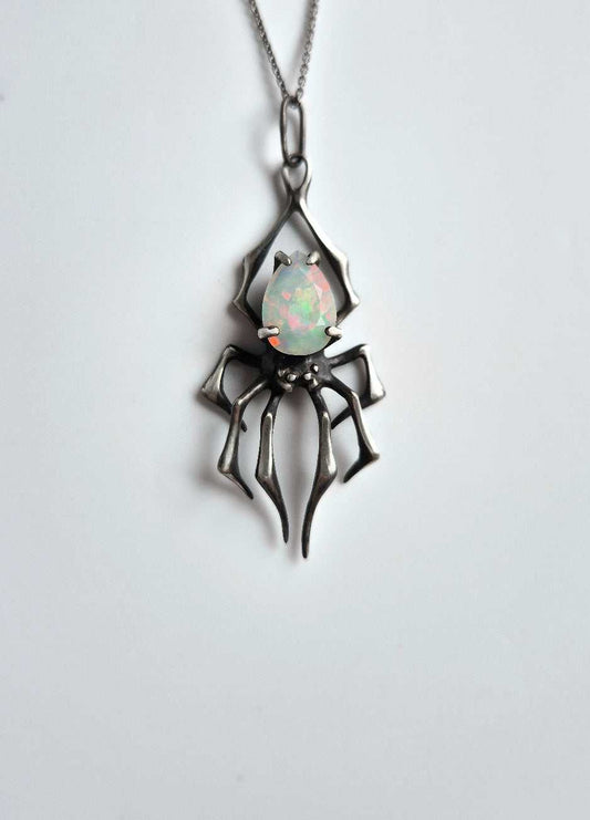 Silver spider necklace with opal gemstone on white background, frontal view
