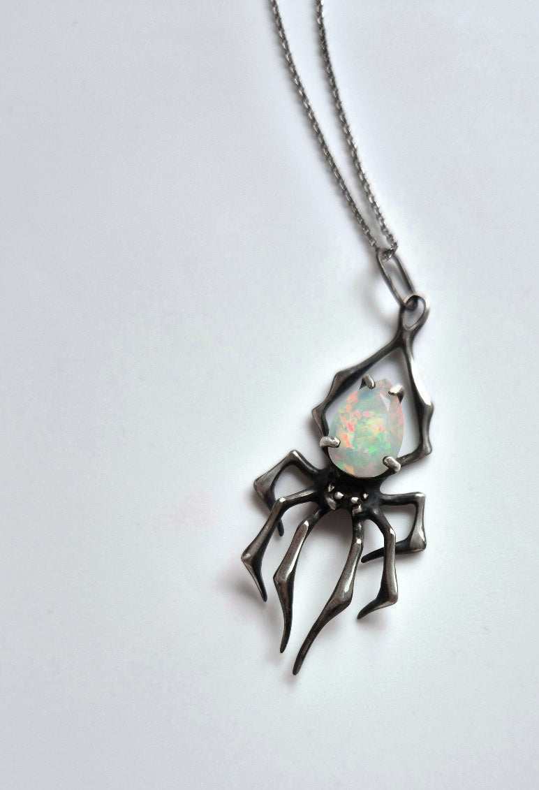 Sterling silver spider pendant with opal, angled top-down view