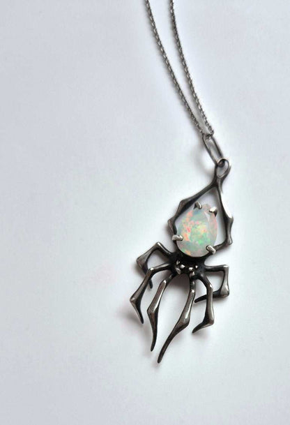 Sterling silver spider pendant with opal, angled top-down view