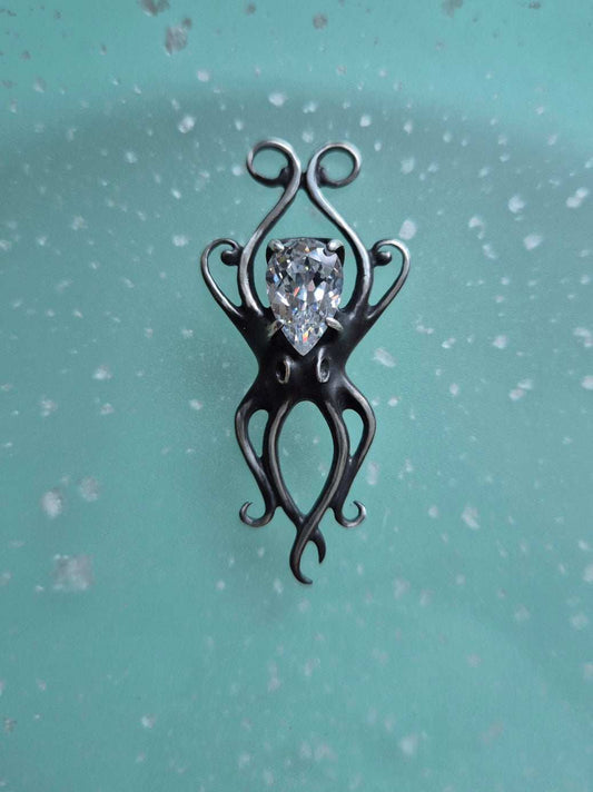 Silver octopus necklace with zircon gemstone displayed on a soft teal background
