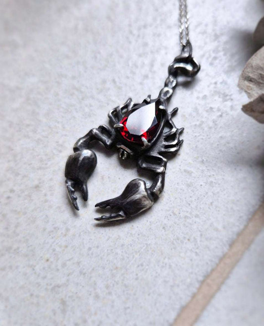 Scorpion necklace in Sterling Silver with Garnet gem, shot of neutral ceramic background