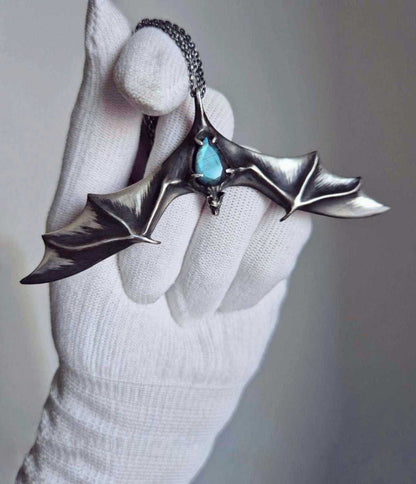 Oxidized sterling silver bat necklace with blue-flash labradorite held in a white-gloved hand